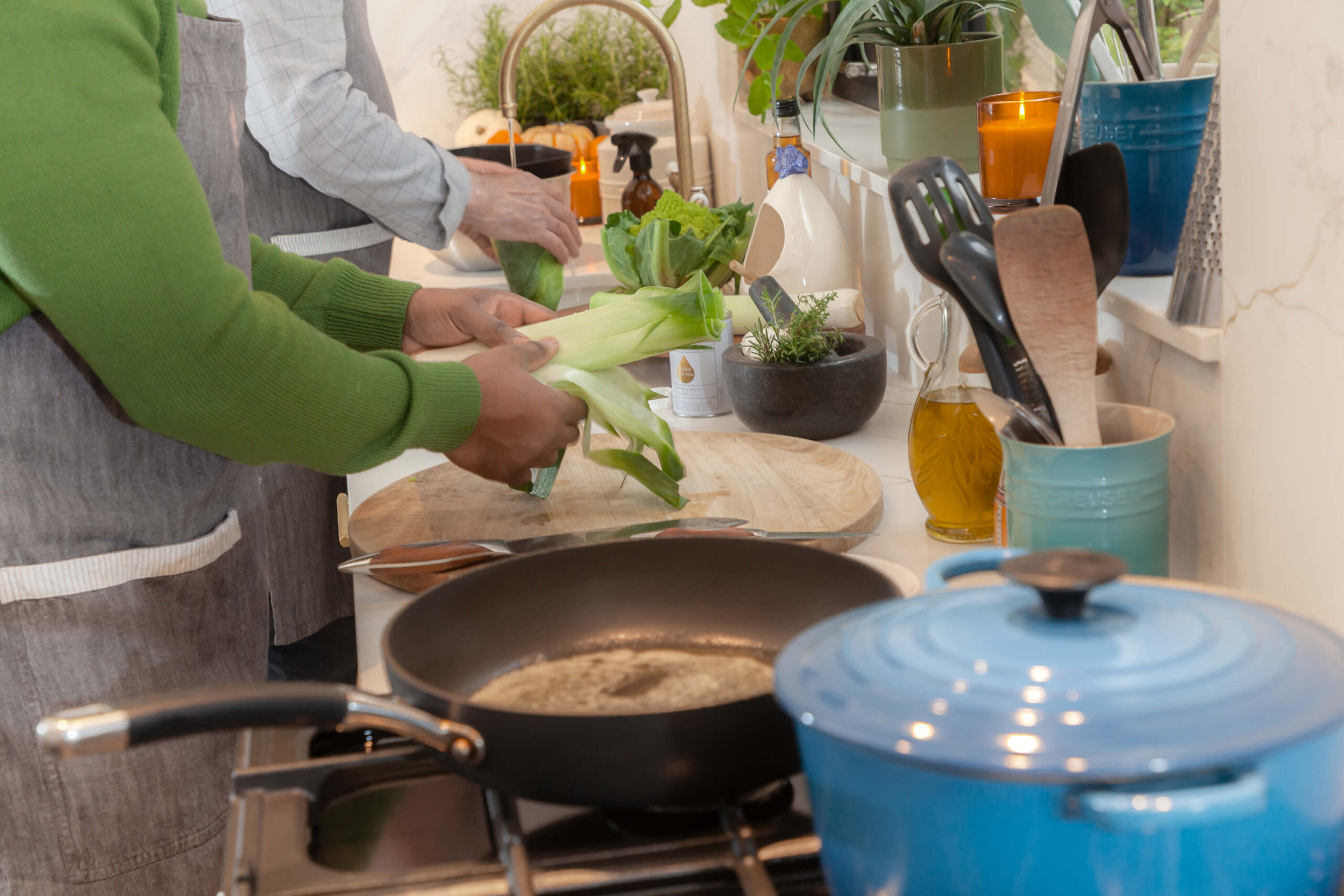 At Home with Angela Gray - shot of kitchen countertop with pots, pans and hands chopping and washing vegetables